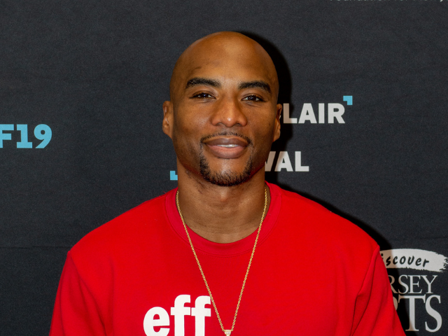 Charlamagne tha God wearing a red t-shirt with a small gold necklace.