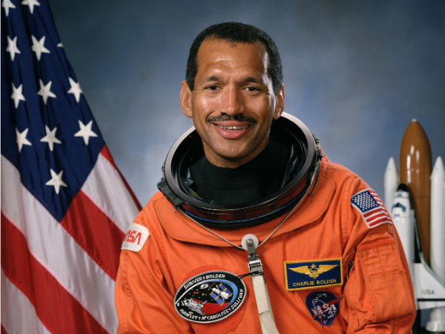 Charles Bolden wearing an orange astronaut suit. 