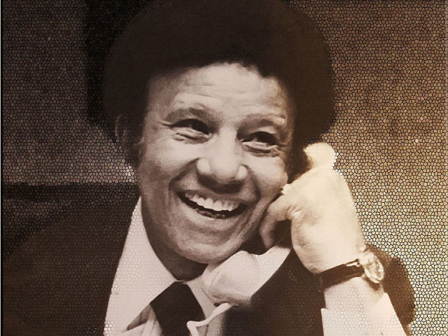 A smiling Hal Jackson holding a phone.