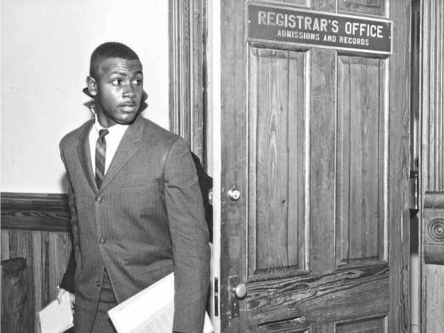 Harvey Gantt wearing a suit and holding papers. 