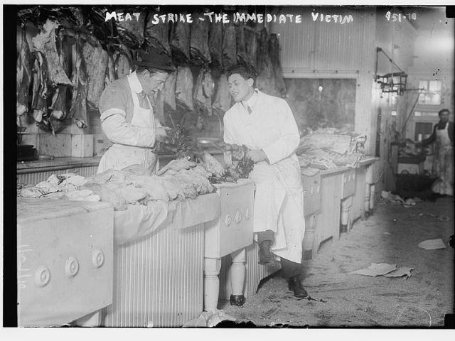two young men standing at meat counter