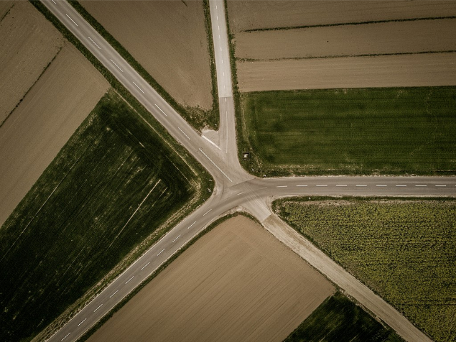 four roads meet up in the center surrounded by fields. 