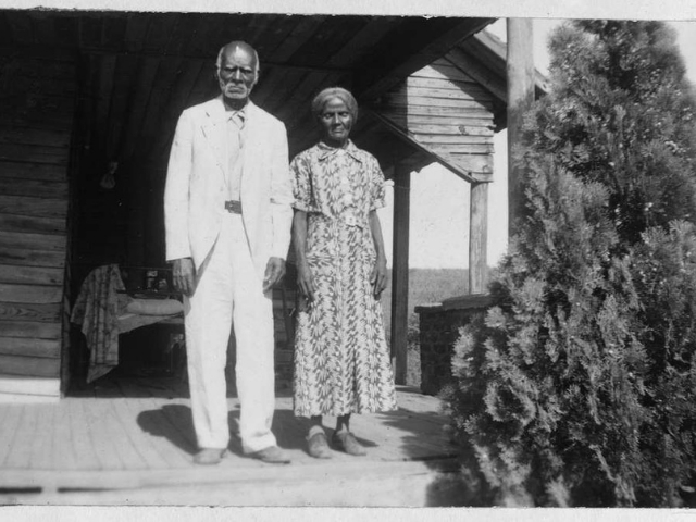 A old man and woman stand on the porch