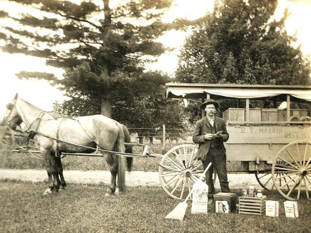 Man standing in front of a wagon next to a horse