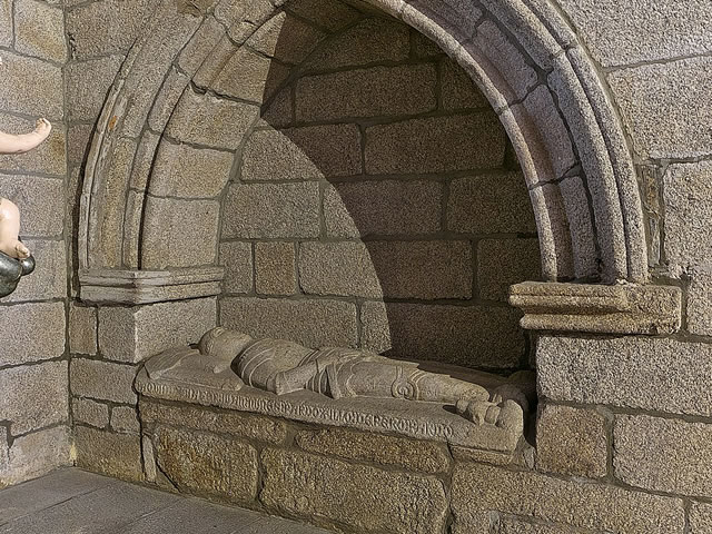 A stone grave sculpture of person laying down. 