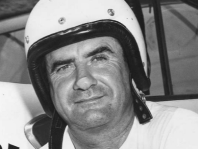 Buck Baker wearing a light and dark color racing helmet 