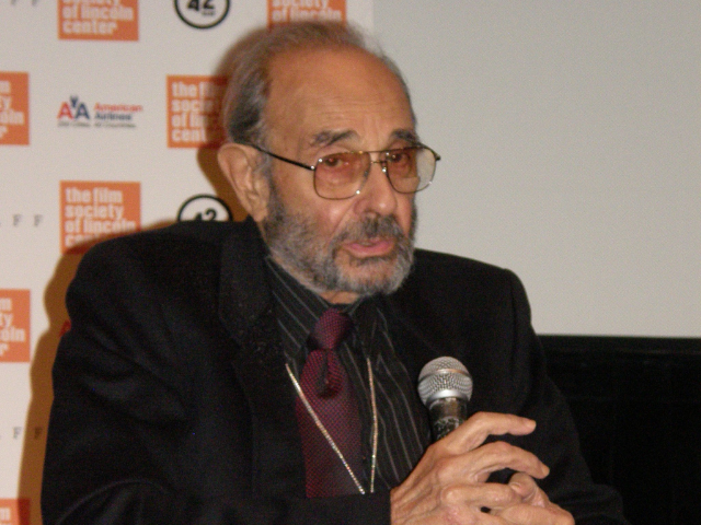 Stanley Donen holding a microphone. 