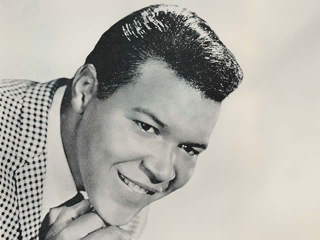 A smiling Chubby Checker wearing a checkered suit jacket.
