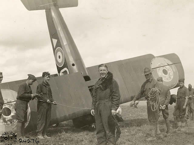 Elliott White Springs standing in front of his plane surrounded by other people. 