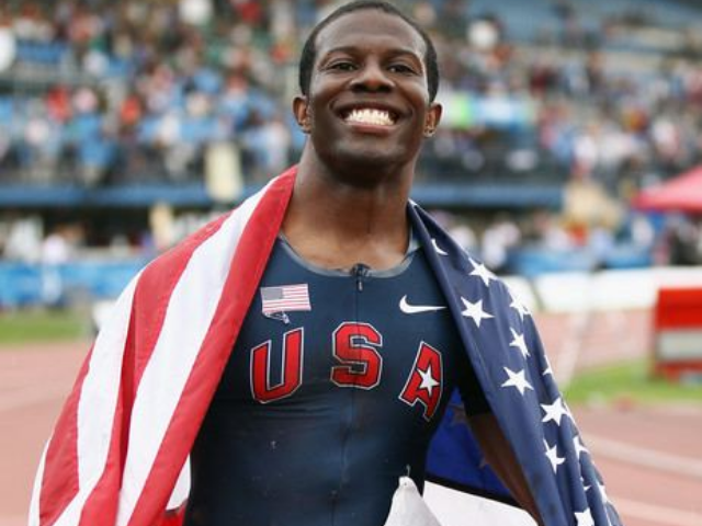 A smiling black man with a red, white, and blue American flag over his shoulders. 